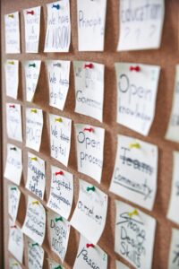 Array of sticky notes pinned on corkboard with business ideas and goals.